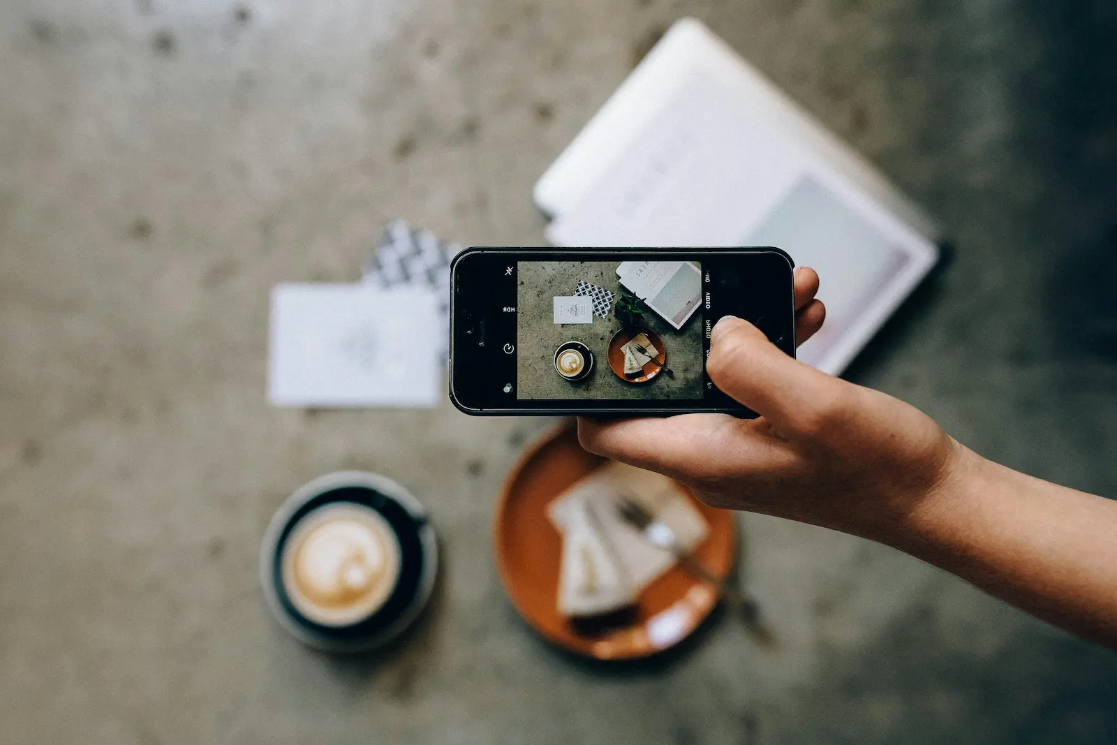 Our Cafe Story. A mobile phone capturing photo of coffee inside cafe